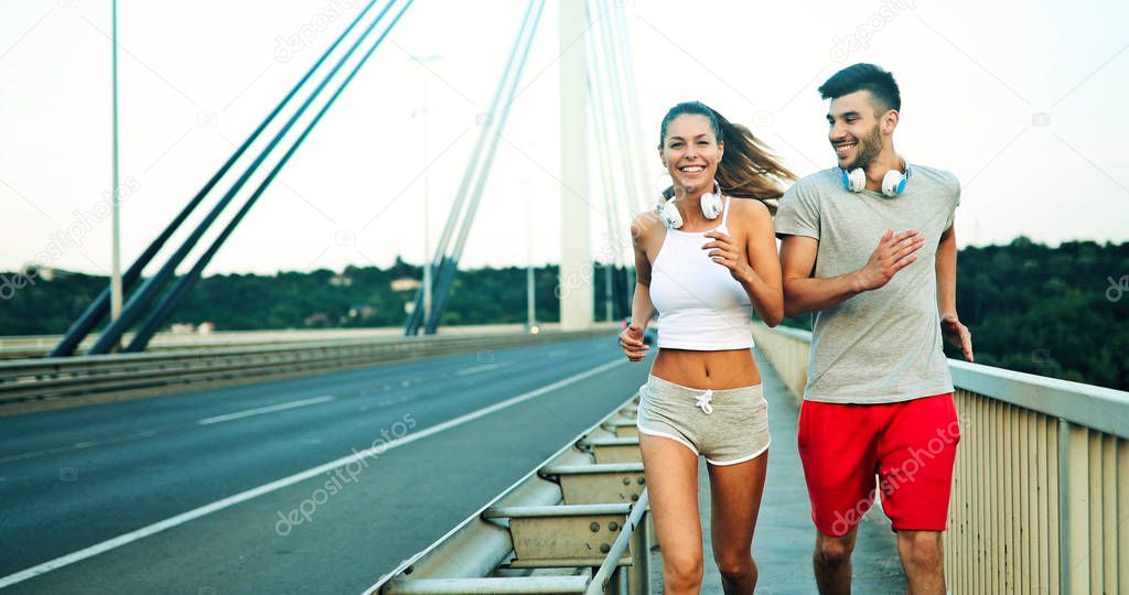 Attractive man and beautiful woman jogging together on bridge