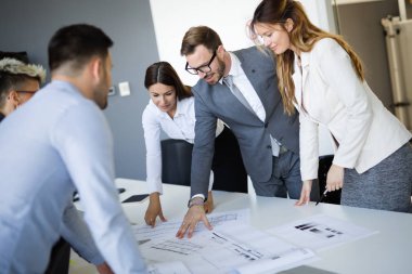 Takım inşaat planları üzerinde birlikte çalışan mimarlar