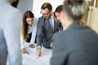 Takım inşaat planları üzerinde birlikte çalışan mimarlar