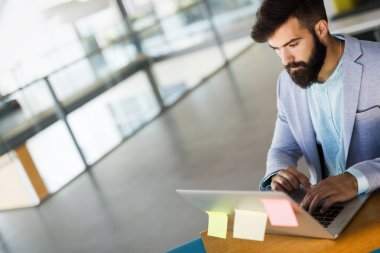 Yakışıklı işadamı modern ofis içinde laptop üzerinde çalışıyor