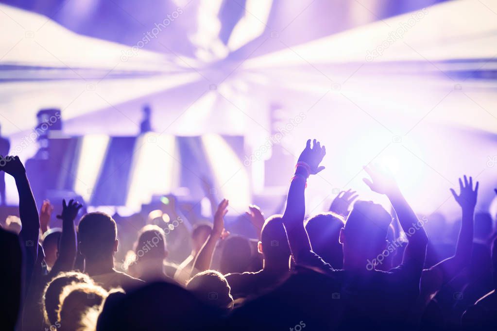 Cheering crowd with hands in air enjoying at music festival