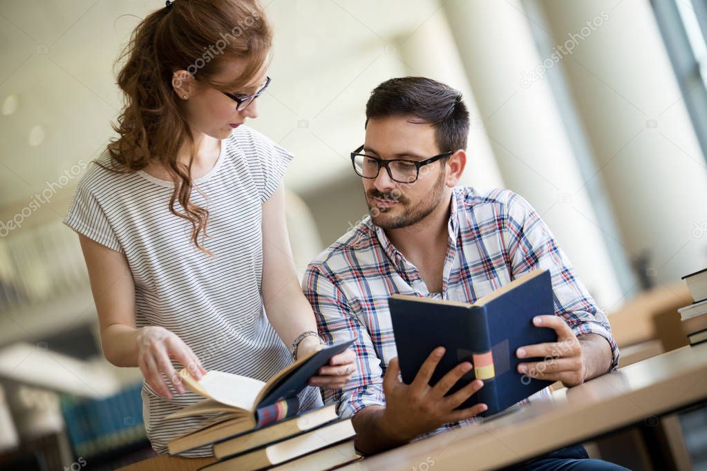 Image of young happy students sitting in library
