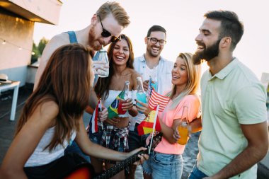 Bir grup mutlu genç arkadaş çatıda parti veriyor.