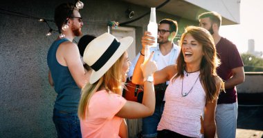 Bir grup mutlu genç arkadaş çatıda parti veriyor.