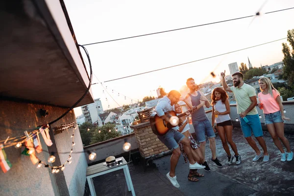 屋上でパーティーをする幸せな若い友人のグループ — ストック写真