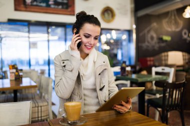 Kafede dijital tablet kullanarak çekici genç kadın