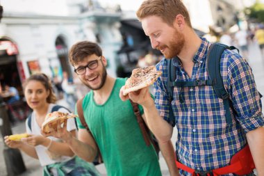 mutlu öğrenciler sokakta pizza yemek
