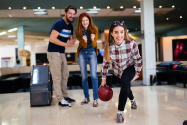 Happy friends having fun and enjoying playing bowling together clipart