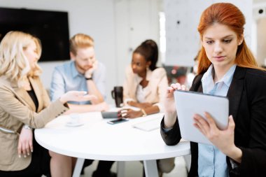 İş adamları yuvarlak masada otururken modern ofiste yönetim kurulu toplantısı yapıyorlar.