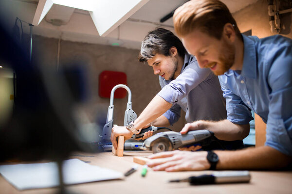 Two creative designers working in workshop with precision tools manufacturing a new product