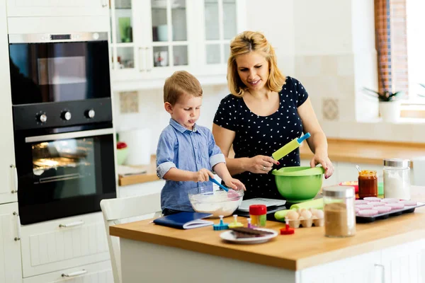 帮助准备松饼在厨房的妈妈的孩子 — 图库照片