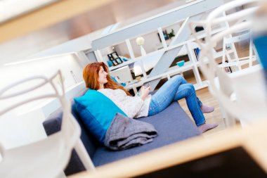 Güzel kırmızı saçlı kadın kanepede otururken telefon kullanma