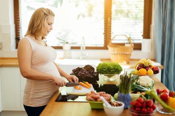 Krásná těhotná žena připravuje jídlo — Stock fotografie