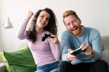 Young attractive happy couple playing video games at home clipart