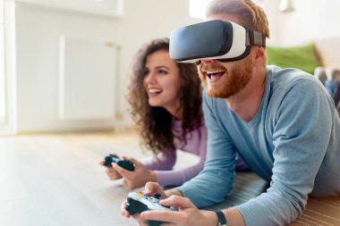 Mutlu genç video oyunları oynarken evde sanal gerçeklik kulaklıklar ile çift.