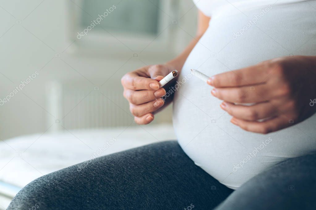 Health minded pregnant woman breaks her last cigarette