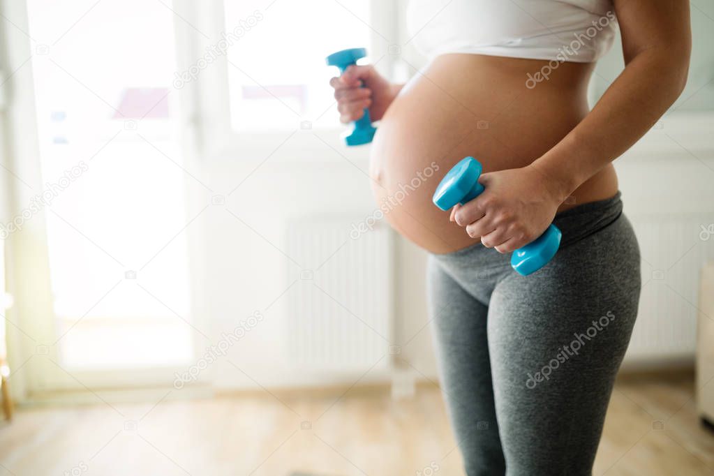 Sporty fitness pregnant woman doing exercises at home