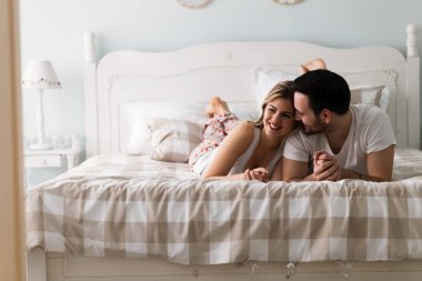 Genç çekici mutlu çift yatakta romantik vakit geçiriyor
