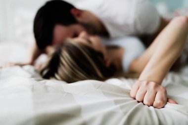 Genç çekici mutlu çift yatakta romantik vakit geçiriyor