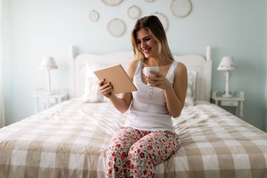 güzel bir genç kadın yatakta dijital tablet kullanma