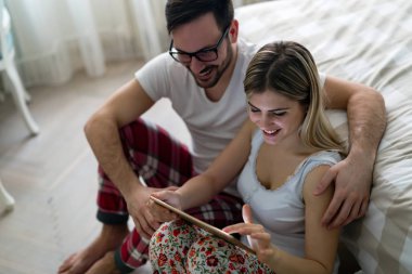 Genç çekici çift yatak odasında dijital tablet kullanma
