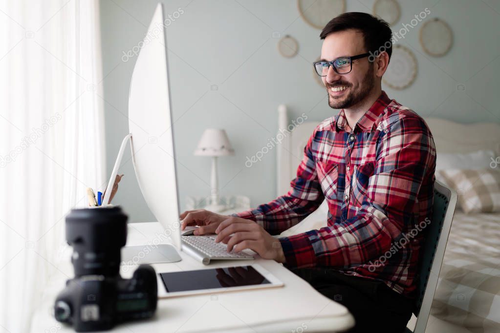 Young handsome designer working on project on his computer at home