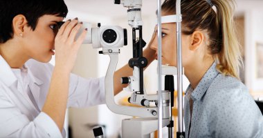 Optometrist examining patient in ophthalmology clinic with professional equipment clipart