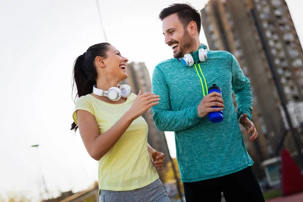 Young fitness couple running together in urban area