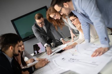 Bir grup mimar ve iş adamı birlikte çalışıyor ve beyin fırtınası yapıyorlar.