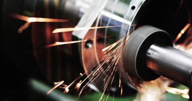 sparks flying while machine griding and finishing metal in factory clipart