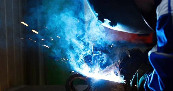 Metal worker welding with torch in metal industry factory