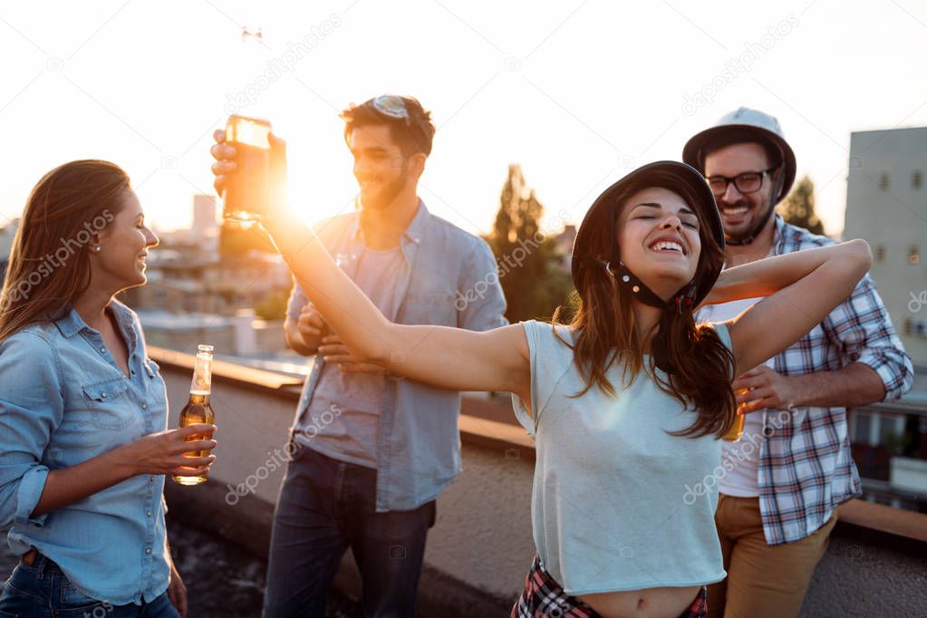 Group of happy young friends having party on rooftop