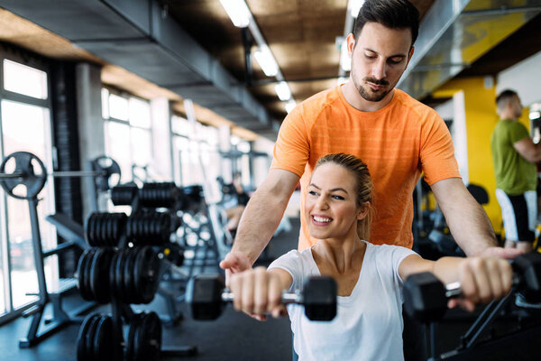 Personal trainer giving instructions to student in gym