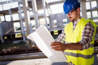 Genç iş adamı inşaat sitesi mühendis mavi baskı ile