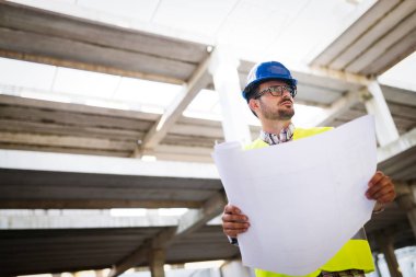 Genç iş adamı inşaat sitesi mühendis mavi baskı ile