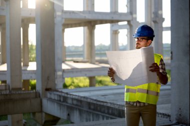 İnşaatta çalışan ve blueprint tutan yakışıklı mühendisi