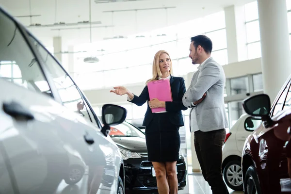职业女性销售人员在与客户在汽车经销商工作期间 — 图库照片
