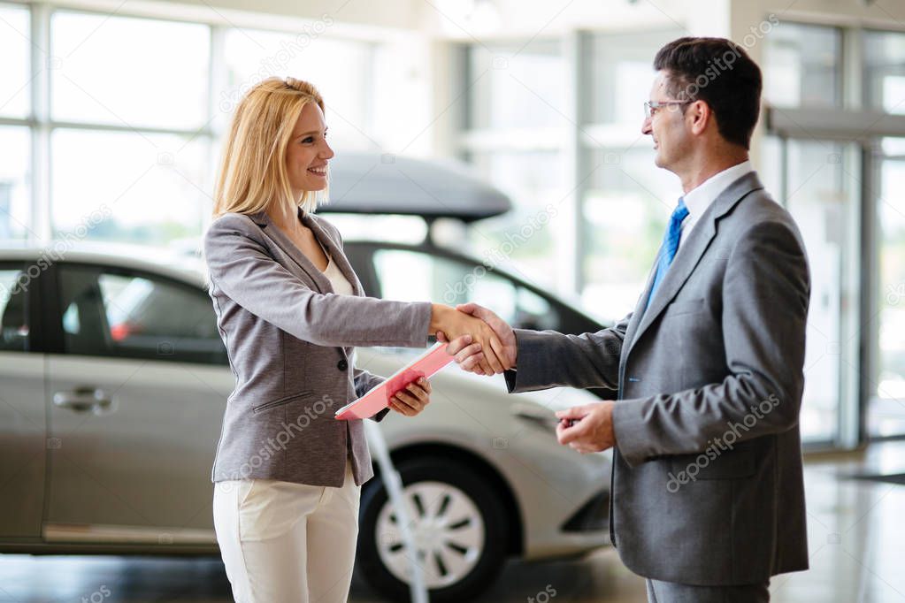 Successful happy businessman in a car dealership - sale of vehicles to customers