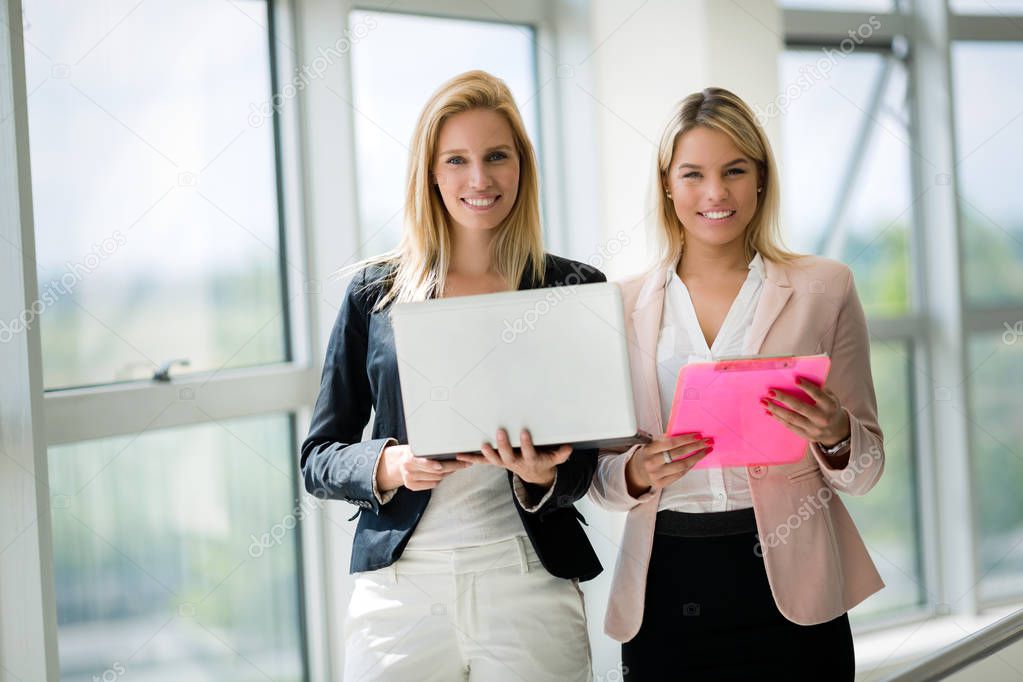 Smiling businesswomen talking and working together in bright office