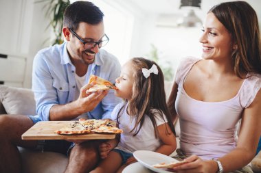 Mutlu aile birlikte evde pizza paylaşımı gülümseyen