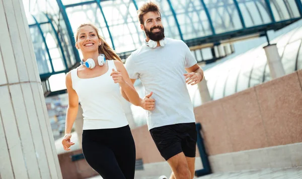 Young fitness couple running together in urban area