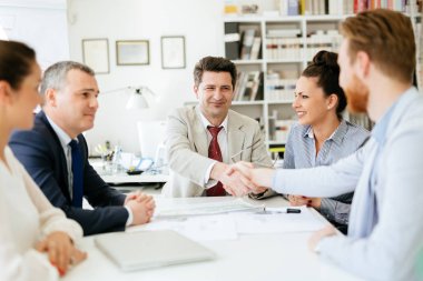 Meşgul genç iş adamları ofiste tokalaşırken