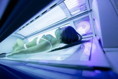 Güzel seksi esmer kadın solaryumda güneşlenme