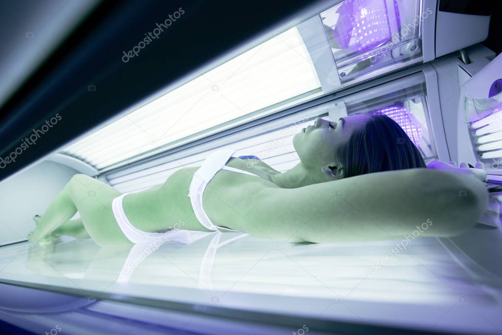 Beautiful sexy brunette woman sunbathing in solarium