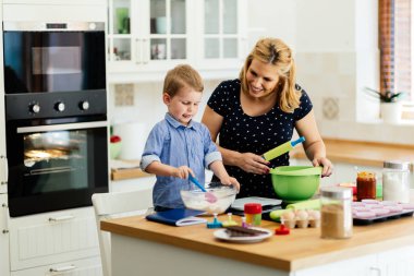 Çocuk modern mutfakta annesine kurabiye yapması için yardım ediyor.