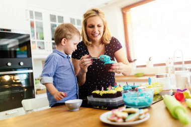 Çocuk modern mutfakta annesine kurabiye yapması için yardım ediyor.