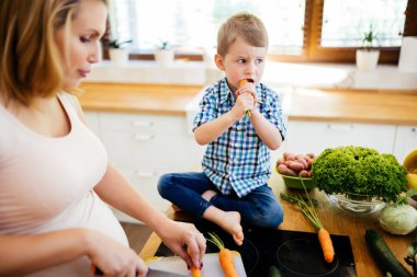 Hamile kadın oğlundan taze sebze ile yemek hazırlama