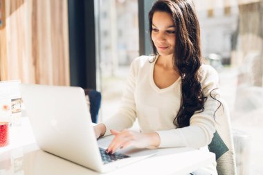 Güzel genç şirin esmer kafede dizüstü kullanarak