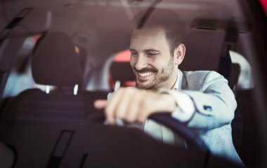 Attractive happy man driving car and smiling clipart