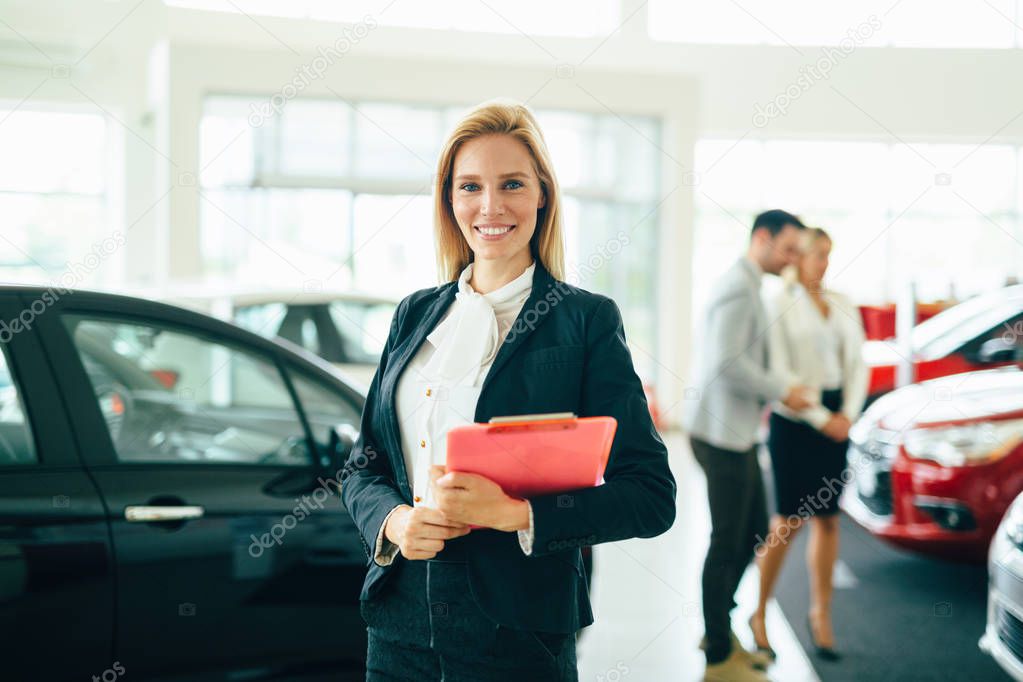 Young beautiful female car sales consultant working in showroom